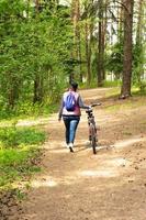 une femme à vélo, une fille européenne s'est arrêtée à vélo pour se détendre dans la forêt photo
