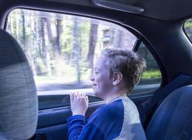 un enfant heureux regarde par la fenêtre d'une voiture ouverte en déplacement, une vue de l'intérieur de la voiture photo