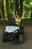 un joli garçon européen monte une voiture pour enfants dans le parc, des manèges pour enfants, des animations dans le parc, une voiture électrique pour enfants photo