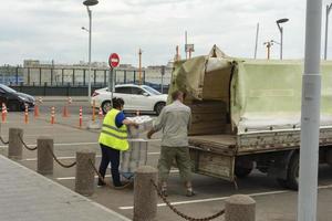 le personnel de service de la gare avec un chariot de fret décharge la voiture avec les marchandises, le service pour le transport des choses photo