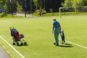 grand-mère joue au ballon avec sa petite-fille sur l'herbe du stade, éducation et soins photo