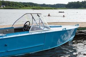 bateau de pêche bleu en aluminium avec un moteur près de la rive du lac, pêche, loisirs actifs, fond de nature. photo