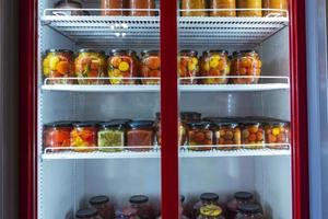 une vitrine réfrigérée avec des conserves de produits maison, un réfrigérateur avec des conserves de fruits et légumes photo