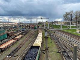 vue aérienne des trains de marchandises colorés sur la gare. wagons avec des marchandises sur le chemin de fer. trains de marchandises. industrie lourde. scène industrielle avec trains, bâtiments de la ville et ciel bleu au coucher du soleil. vue de dessus photo