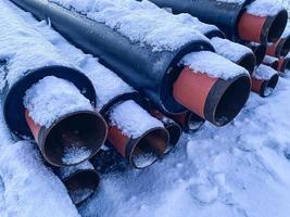 matériel pour les travaux de réparation. tuyaux d'égout pour la pose des communications. longs tuyaux noirs en polypropylène sur neige pure blanche avec pointes rouges photo