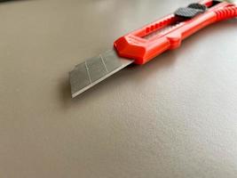 couteau de papeterie de bureau pointu rouge avec une lame de coupe de papier sur un bureau de bureau. travail d'entreprise photo