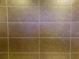 beaux carreaux de mur en céramique coûteux chic doré dans la salle de bain avec des coutures. arrière-plan, texture photo