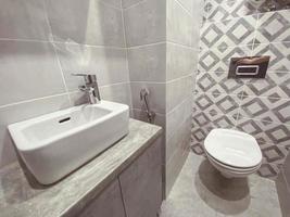 bain moderne et élégant dans un appartement résidentiel. évier en pierre sur un comptoir en pierre. la toilette en porcelaine est recouverte d'un couvercle. montage suspendu. douche hygiénique à côté des toilettes photo