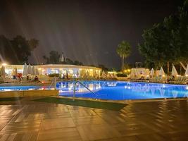 belle piscine de nuit avec parasols et chaises longues et palmiers dans un hôtel en vacances dans une station balnéaire du sud de l'est tropical chaud touristique photo