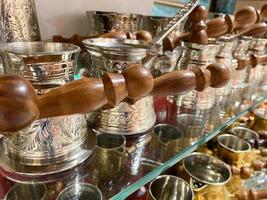 beaux turcs dorés avec un manche en bois pour préparer du café décoratif oriental sculpté brillant dans une boutique de souvenirs touristiques photo