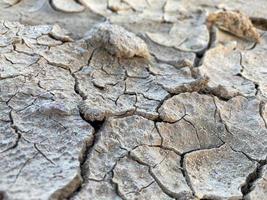 gris sec fissuré belle texture du sol aride et de l'argile du désert. l'arrière-plan photo