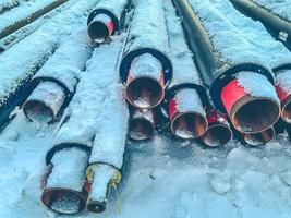 matériel pour les travaux de réparation. tuyaux d'égout pour la pose de communications dans une zone résidentielle. longs tuyaux en polypropylène noir. les tuyaux se trouvent sur la neige blanche photo