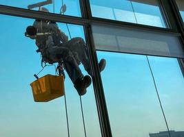 alpinisme industriel, un homme lave les vitres d'un immeuble de grande hauteur photo