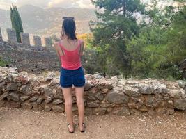 fille touriste regarde l'ancien mur antique de la forteresse médiévale du château dans la station balnéaire du sud des pays de l'est tropical chaud touristique photo