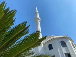 Nouvelle mosquée islamique arabe blanc moderne grand musulman pour les prières avec une haute tour dans un pays de l'est tropical chaud touristique station du sud photo