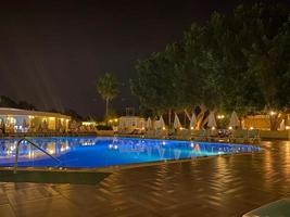 belle piscine de nuit avec parasols et chaises longues et palmiers dans un hôtel en vacances dans une station balnéaire du sud de l'est tropical chaud touristique photo