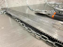 de grands ciseaux métalliques tranchants en fer, des couteaux à métaux et une scie à chaînes reposent sur une table en fer. outils de serrurier à main. l'arrière-plan photo
