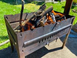 un feu allumé pour les charbons dans un gril en fer rouillé pour la cuisson du barbecue et de la viande frite sur le feu photo