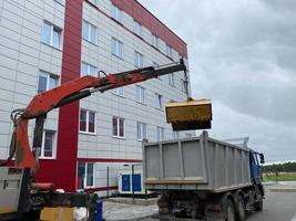 un grand camion à ordures puissant décharge les ordures avec un manipulateur pour le recyclage ultérieur des ressources photo