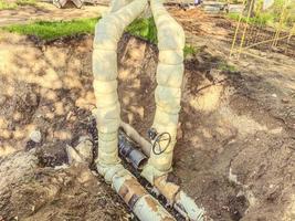 pose de communications souterraines pour les bâtiments résidentiels. tuyaux de plomberie en noir avec une vanne pour réguler le débit d'eau photo