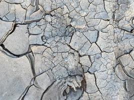 gris sec fissuré belle texture du sol aride et de l'argile du désert. l'arrière-plan photo