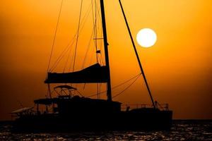 silhouette de bateau au coucher du soleil photo