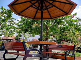 bancs et parasols de lieu de repos en bois et fer brun noir, ciel bleu vif dans le jardin de la ville de madiun en indonésie. photo