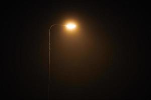 un lampadaire de nuit brille d'une faible lumière jaune mystérieuse à travers le brouillard du soir, espace de copie photo