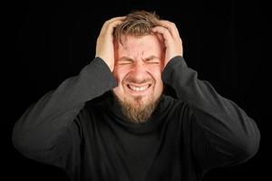 surmenage, concept de douleur à la tête. jeune homme en pull col polo noir. photo