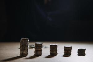 économiser de l'argent à la main en mettant des pièces sur la pile sur la table avec le soleil. concept finance et comptabilité photo