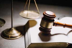 concept de justice et de droit. juge masculin dans une salle d'audience avec le marteau, travaillant avec, clavier d'ordinateur et d'accueil, lunettes, sur table à la lumière du matin photo