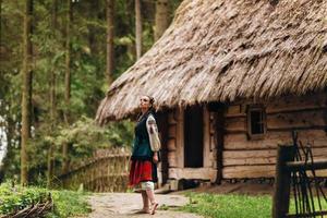 fille dans une robe brodée est debout dans la cour et regarde dans le ciel photo