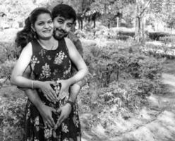 couple indien posant pour une séance photo de maternité. le couple pose dans une pelouse avec de l'herbe verte et la femme étale sa bosse de bébé dans le jardin de lodhi à new delhi, inde - noir et blanc