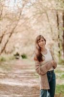 portrait d'une jeune fille aux cheveux bruns, en cardigan, lors d'une promenade en forêt. photo