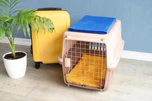 porte-animal en plastique ouvert ou cage pour animal de compagnie et valise jaune sur le sol à la maison, espace pour copie photo