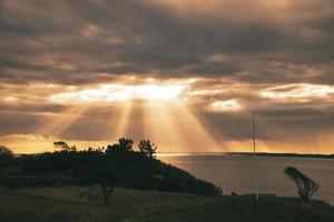 sur la côte des centaines. les rayons du soleil traversent le ciel dramatique à travers les nuages photo