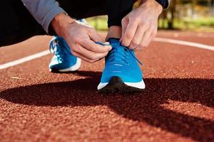 le coureur se prépare pour la course, attache les lacets des baskets photo