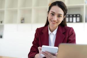 femme d'affaires asiatique utilisant une calculatrice et un ordinateur portable pour faire des finances mathématiques sur un bureau, fiscalité, rapport, comptabilité, statistiques et concept de recherche analytique