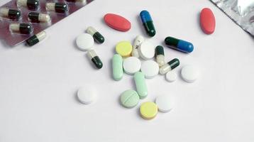 Pilules et comprimés multicolores sur fond blanc photo