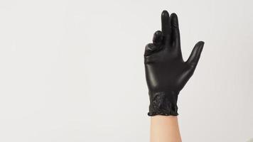 la main porte des gants en latex noir sur fond blanc. photo