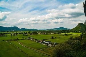 rizières, ciel et montagnes vue grand angle du temple de la grotte du tigre kanchanaburi, thaïlande photo