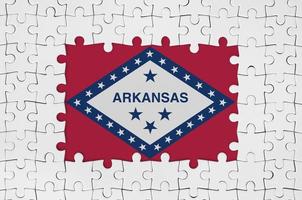 Drapeau de l'état américain de l'Arkansas dans le cadre de pièces de puzzle blanches avec partie centrale manquante photo