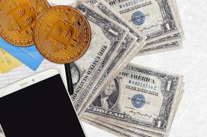 1 billets d'un dollar américain et bitcoins dorés avec smartphone et cartes de crédit. concept d'investissement en crypto-monnaie. minage ou commerce de crypto photo