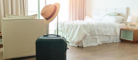 bagage noir avec chapeau dans une chambre d'hôtel moderne après l'ouverture de la porte. bagages pour le temps de voyager, service, voyage, voyage, vacances d'été et concepts de vacances photo