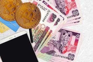 Billets de 20 roupies sri lankaises et bitcoins dorés avec smartphone et cartes de crédit. concept d'investissement en crypto-monnaie. minage ou commerce de crypto photo