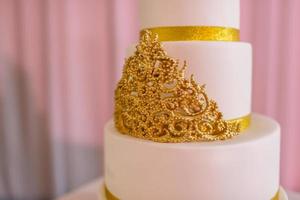 photo recadrée du gâteau de mariage. 3 étages recouverts de fondant ivoire vaporisé de spray nacré et de roses dorées en pâte à sucre. gâteau de mariage avec de l'or. mise au point sélective