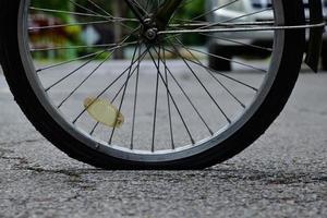 roue arrière du vélo qui est à plat et garée sur le trottoir à côté de la route. photo