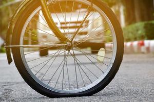 roue arrière du vélo qui est à plat et garée sur le trottoir à côté de la route. photo