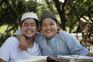 les garçons musulmans asiatiques s'assoient ensemble dans le parc de l'école pour lire et apprendre leur activité quotidienne et faire leurs devoirs pendant leurs temps libres avant de rentrer à la maison, mise au point douce et sélective. photo