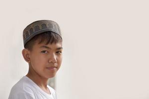 portrait jeune garçon islamique ou musulman d'asie du sud-est en chemise blanche et chapeau, isolé sur blanc, mise au point douce et sélective. photo